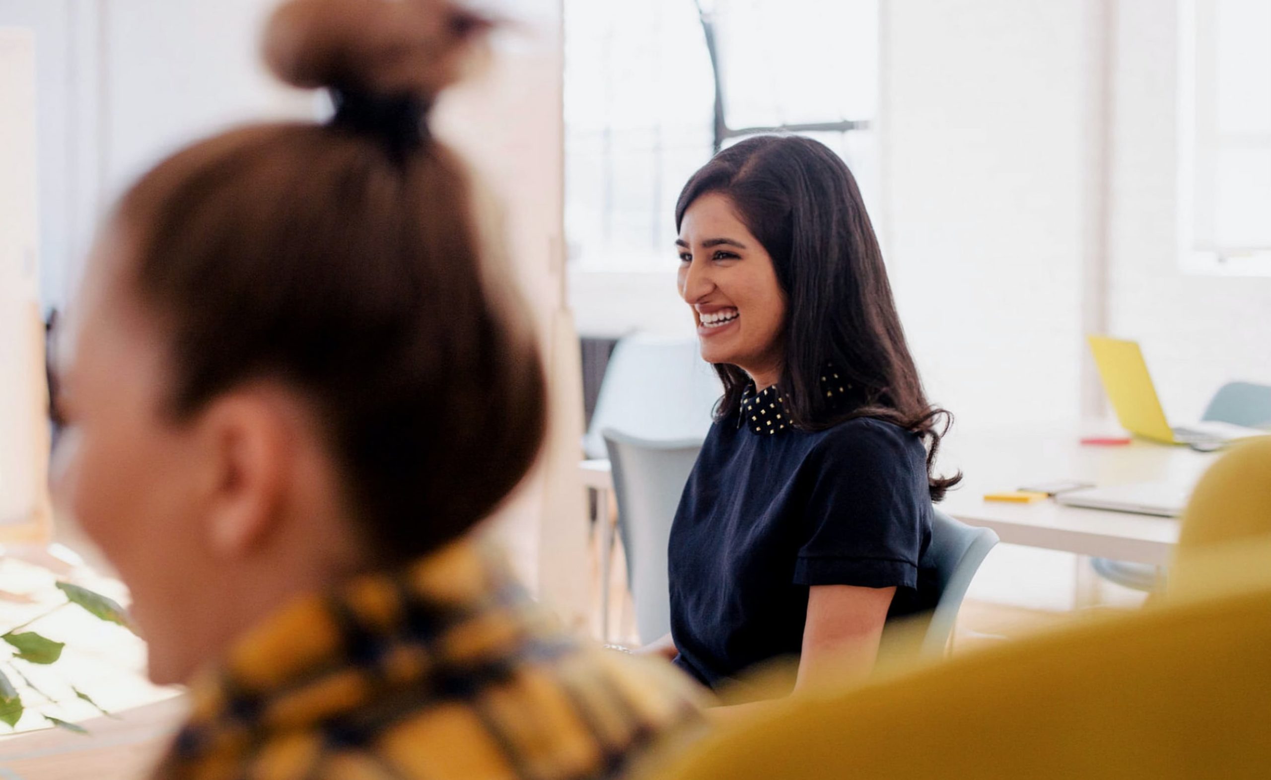 Two women speaking to each other in a meeting