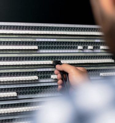 man plugging cables into a sound board
